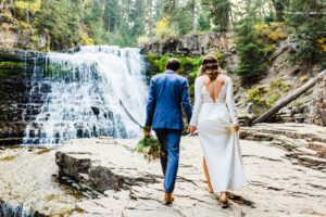 couple walking by waterfall wedding in spring