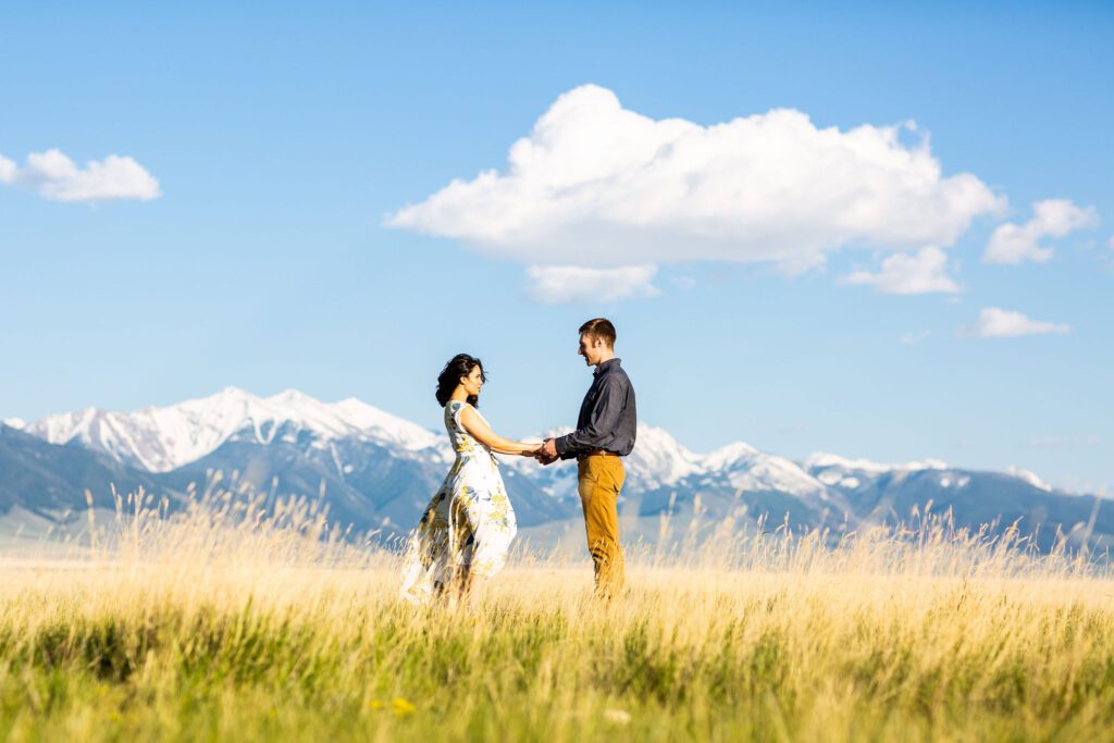 a beautiful couple holding hands with montana mountains in the backdrop