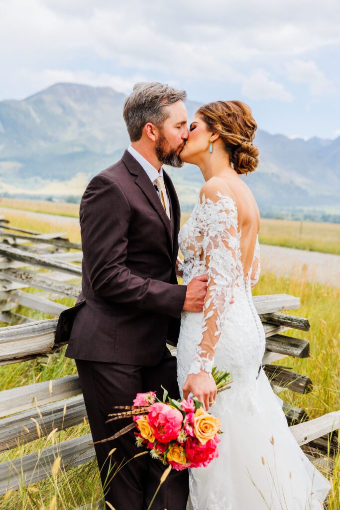 romantic bride and groom kiss with mountains in the backdrop in whitefish, mt