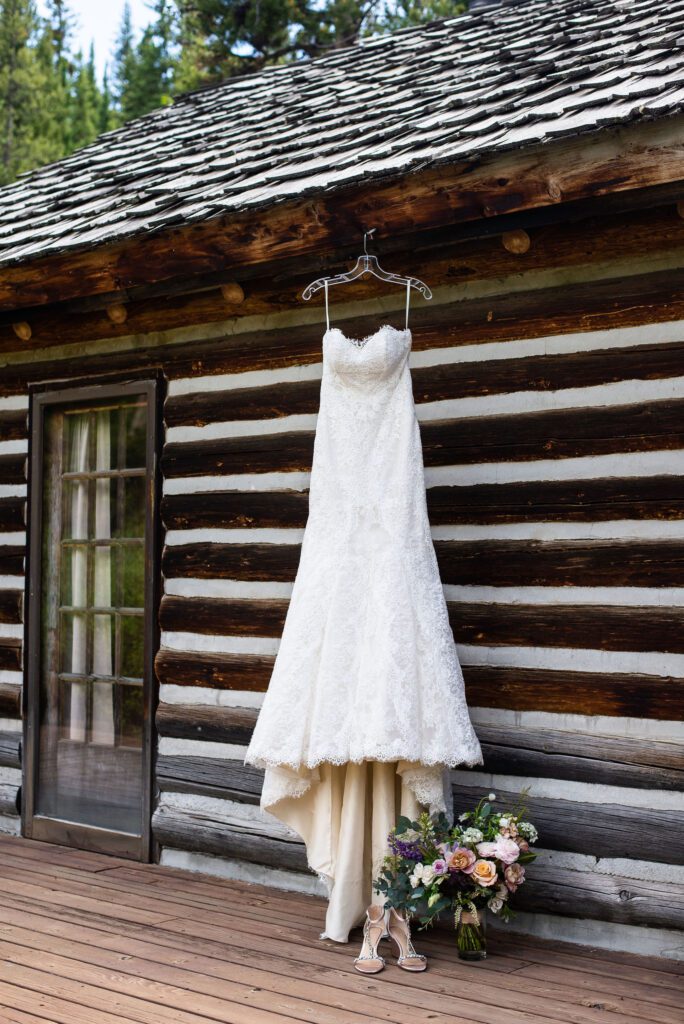 wedding dress propped up against a rustic wooden cabin